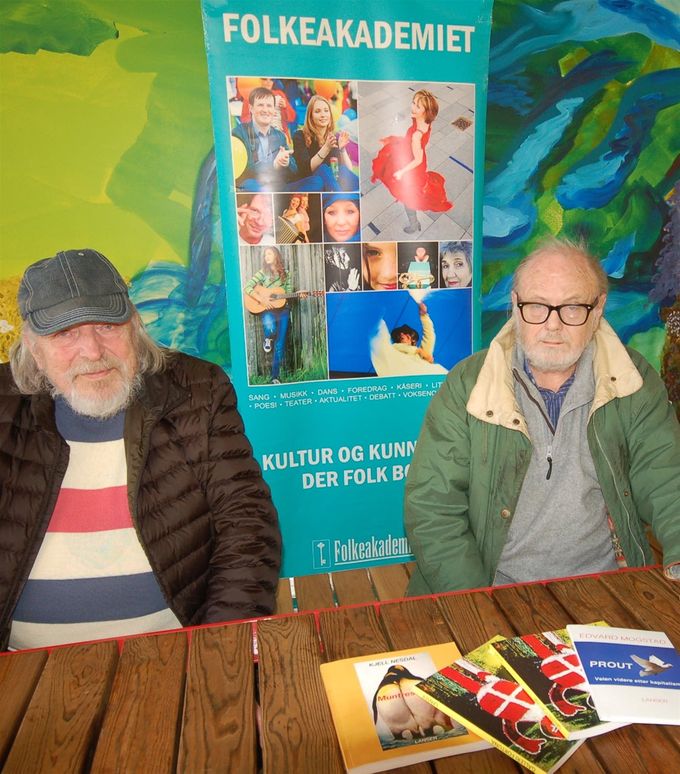 Foto og bildetekst: Rolf Kristiansen: FARGERIKT: Svein Lanser (til venstre) og Kjell Nesdal er ikke som amatører å regne, verken når det gjelder kunsten eller i livet. Her med et utvalg av deres bøker på bordet og en av Folkeakademiets plakater i bakgrunnen.